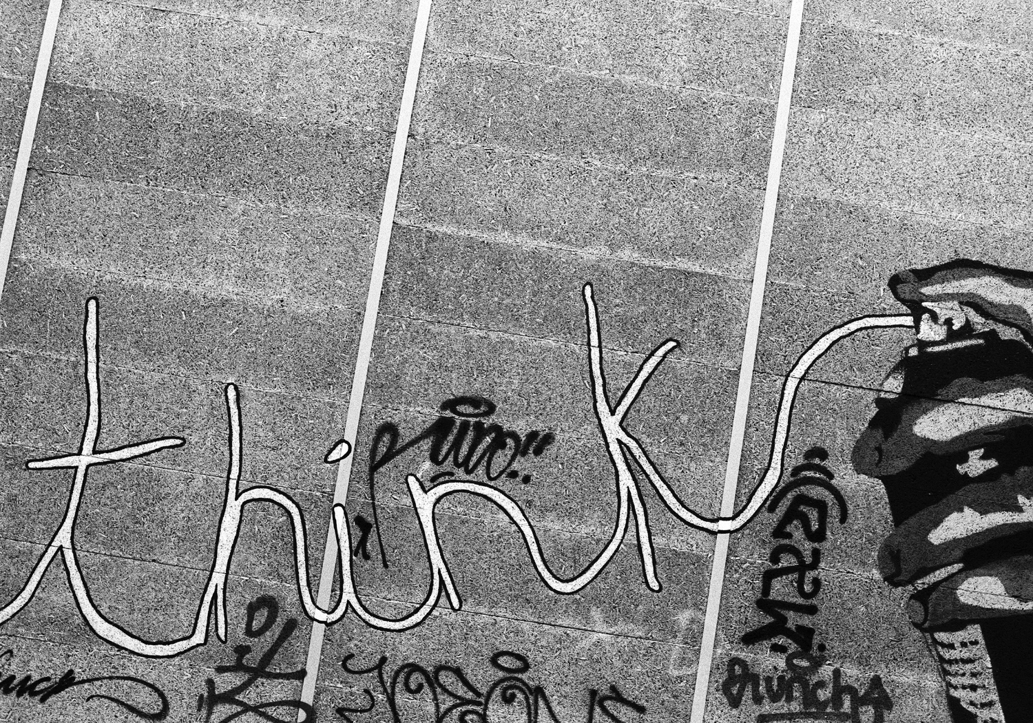 Graffiti with words "think" on the wall, and the words are coming from a spray can.