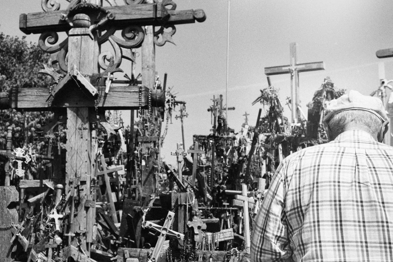 Person standing amongst crosses, also above his head is huge white highlight, making him look like saint