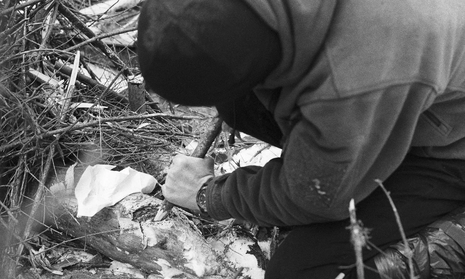 Person attempting to make fire by pushing a stick against another stick