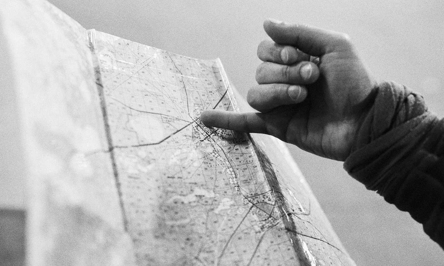 Person's hand pointing towards a specific point on a map